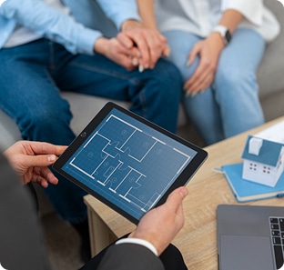 Conseiller immobilier présentant un plan de maison sur tablette à des clients lors d’un rendez-vous personnalisé.